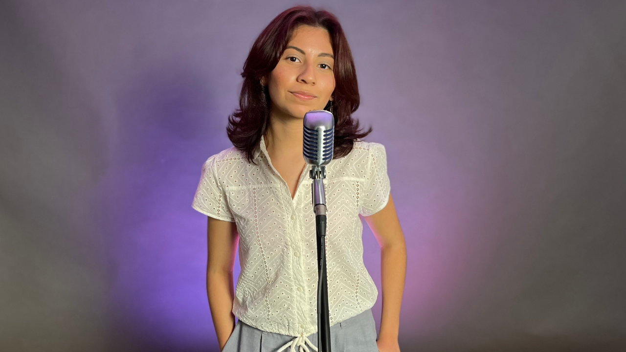 Indie Maryland-based artist Mia Celeste poses in front of microphone smiling slightly.