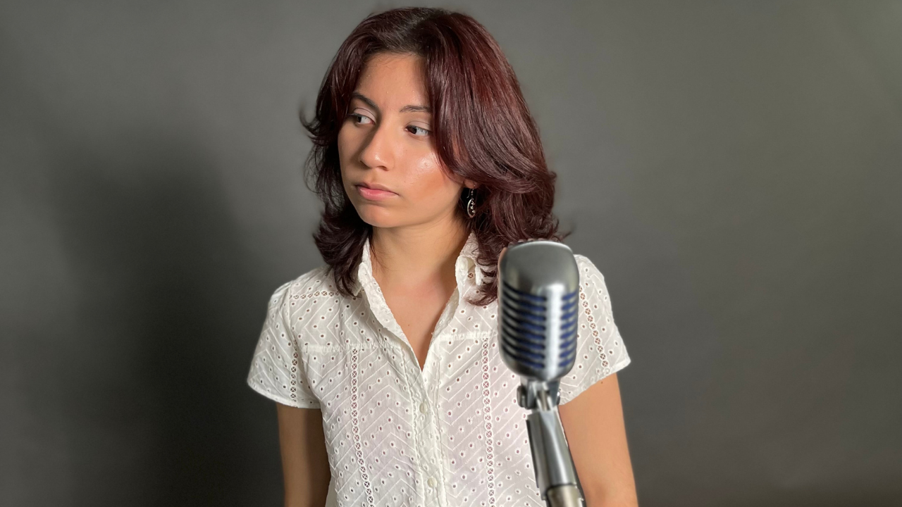 Indie Maryland-based artist Mia Celeste poses in front of microphone smiling slightly.