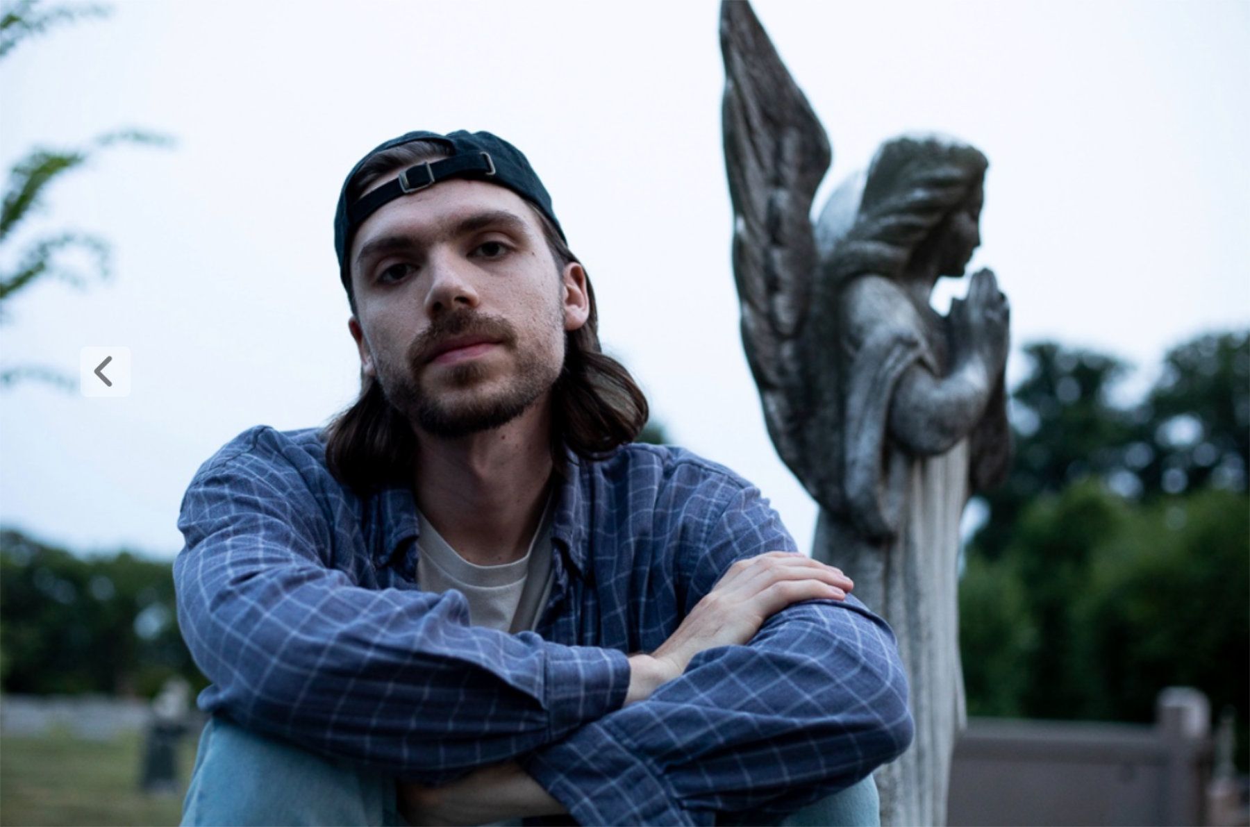 A portrait of lead singer Mike Dzambasow sitting in a graveyard.